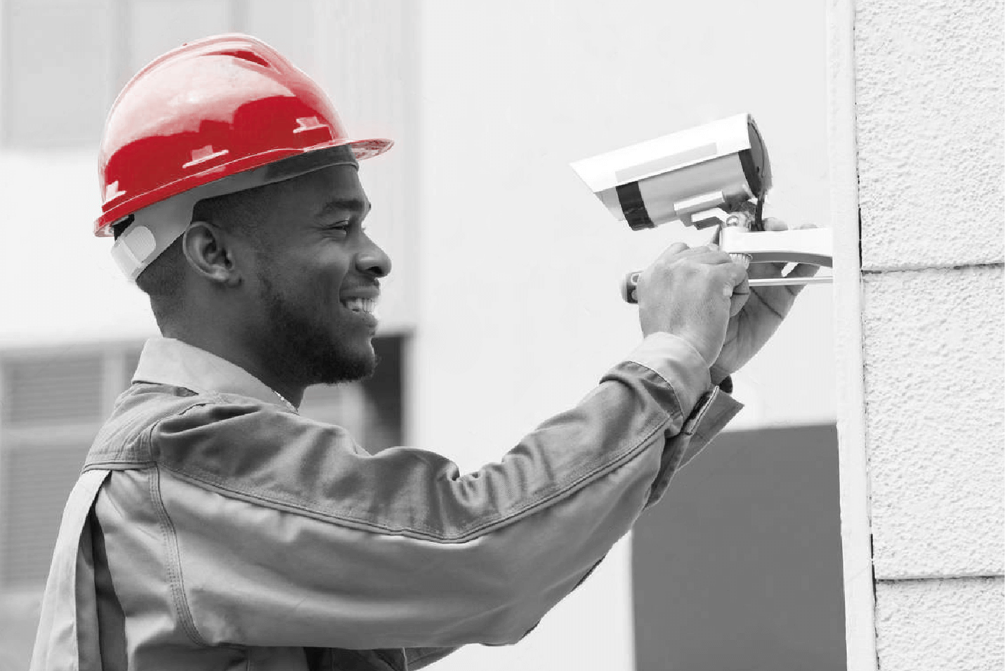 worker installing camera on side of building